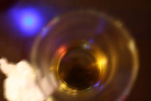 Top-down view into a glass of whisky with colourful bar lights