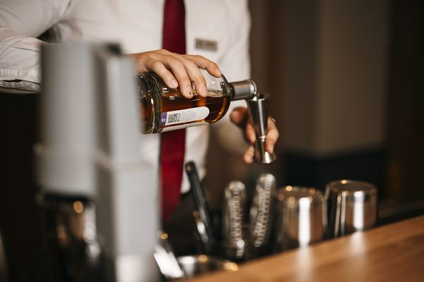 Bartender pouring a measure of whisky into a jigger