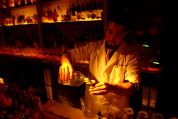 Bartender pouring a drink behind a warmly lit bar