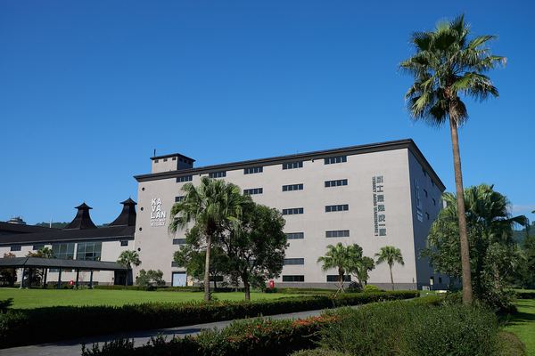 Kavalan whisky ageing warehouse with palm trees under blue sky, Yilan, Taiwan