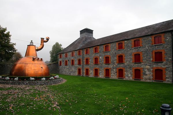 Giant copper still on the lawn in front of the stone Old Midleton Distillery, County Cork