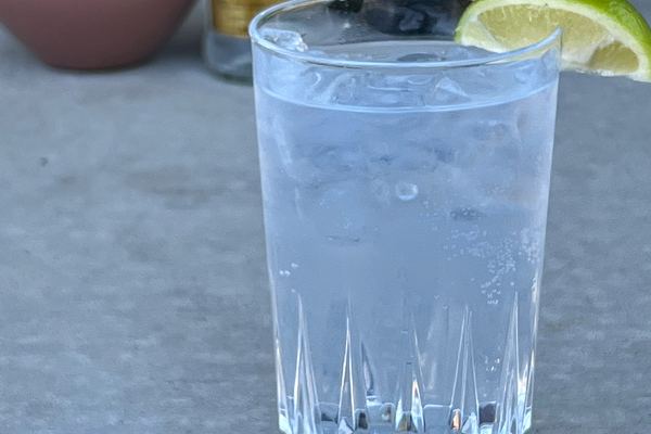 Tall highball glass filled with ice, tonic and a wedge of lime