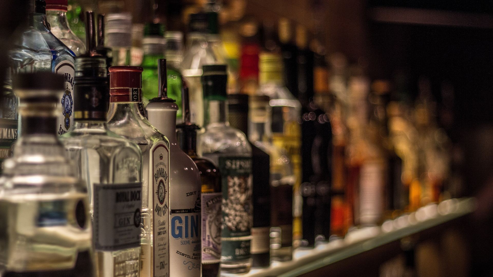 Shelves of whisky bottles under warm light, the starting point of our whisky for beginners guide