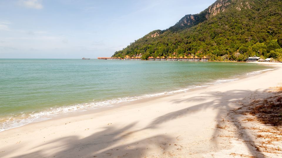 White sand beach and turquoise sea on Langkawi island with forested hills
